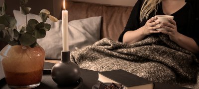 Woman in a sofa with blanket and a warm cup of tea