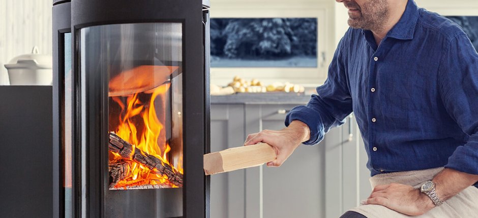 A man who put logs in the wood stove Jøtul F 373 Advance 
