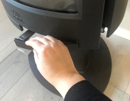The hand which open the door of the wood stove carefully 