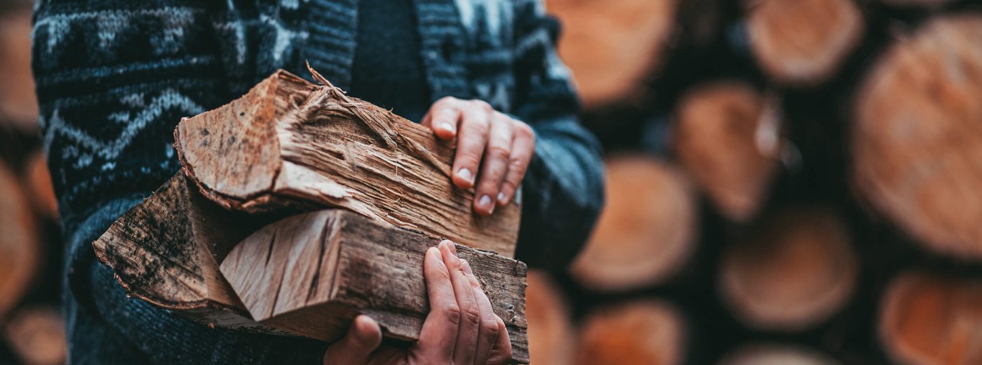Man with cardigan holding firewood in his arms